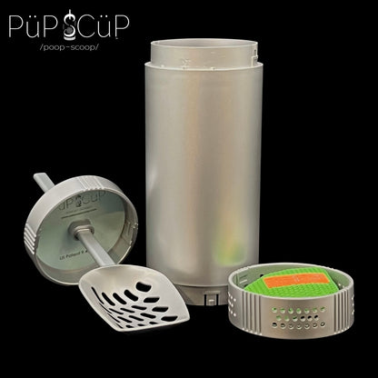 Space-saving PÜP SCÜP™ litter scoop containment system showcasing its compact plastic outer cylinder, metal scoop with a plastic lid, and attached plastic bottom vented cavity featuring tamper-resistant locking mechanisms to deter accidental opening and house the replaceable NōSmell™ charcoal odor control bag.